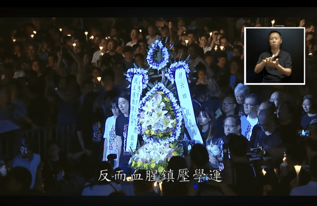 庭上播放 2018 年六四集會獻花環節,畫面可見鄒幸彤、何俊仁。(網上截圖)