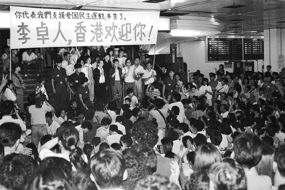 1989 年 6 月 8 日,李卓人返抵香港時,獲多人拉橫額接機,其妻鄧燕娥在身後拭淚。(陳清華提供照片)